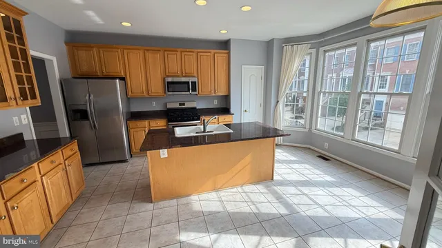 a large kitchen with stainless steel appliances a stove a refrigerator a sink a oven with granite countertops and cabinets