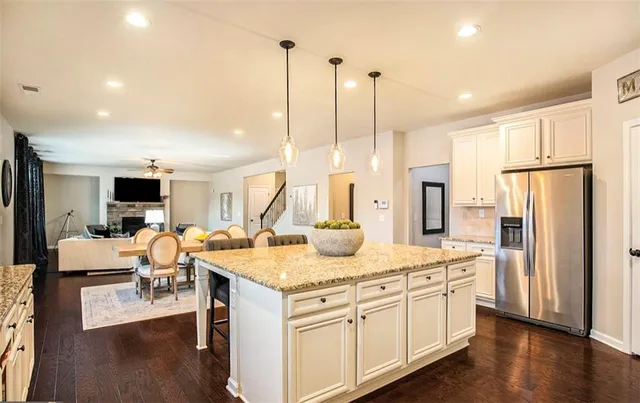 a kitchen with stainless steel appliances kitchen island granite countertop a stove refrigerator and cabinets