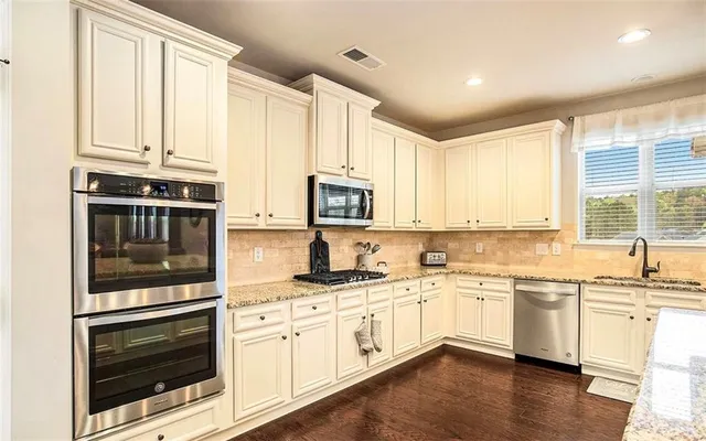 a kitchen with stainless steel appliances granite countertop a stove and white cabinets