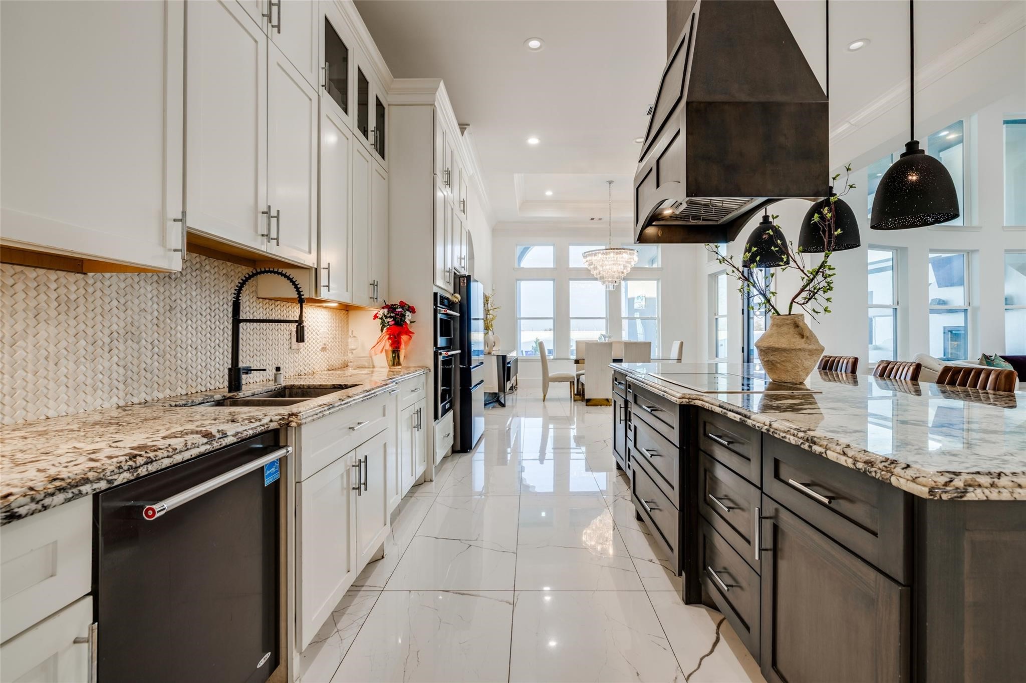 4821 Walters Road Richmond, TX 77469 - Photo 27 of 50 his designer gourmet kitchen makes a bold statement with soaring custom cabinetry, dramatic ceiling-height finishes, and an oversized waterfall island perfect for entertaining. Featuring premium stainless steel appliances, elegant pendant lighting, marble-style flooring, and rich contrasting accents, the space blends timeless sophistication with modern functionality. The open-concept layout, expansive prep areas, built-in wine storage, and abundant natural light create a luxurious culinary experience