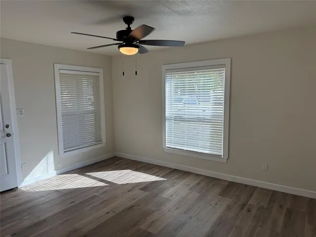a view of an empty room with wooden floor and a window