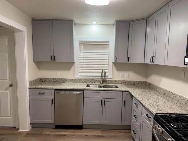 a kitchen with granite countertop cabinets sink and stainless steel appliances