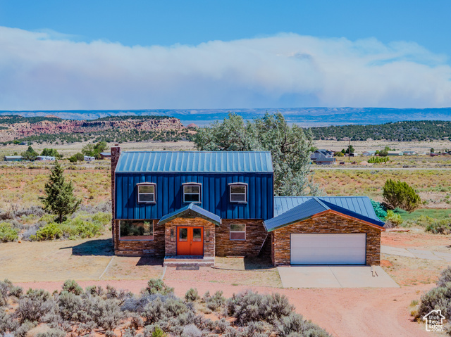 6178 East Zion Road Kanab, UT 84741 - Photo 1 of 48 View of front of property with stone siding, concrete driveway, a standing seam roof, a metal roof, and a chimney