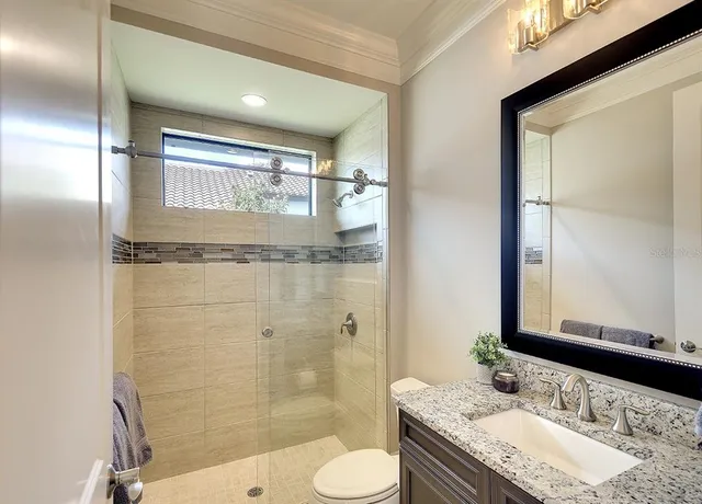 a bathroom with a granite countertop sink toilet a mirror and shower