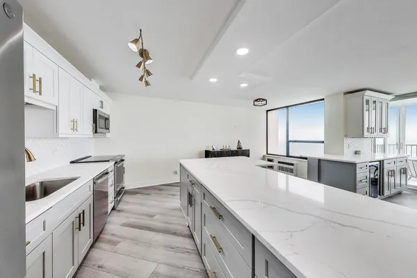 a large kitchen with stainless steel appliances a sink stove and cabinets