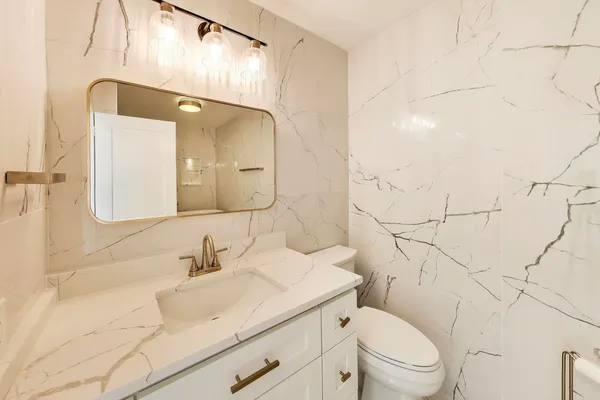 a bathroom with a granite countertop sink mirror vanity and toilet