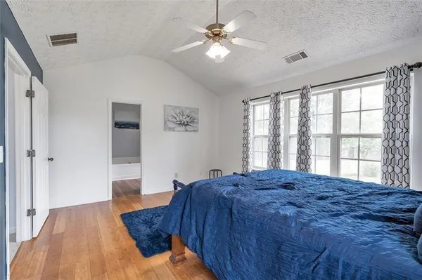 a bed sitting in a spacious bedroom next to a window