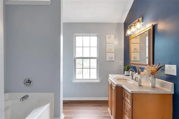 a bathroom with a tub sink and mirror