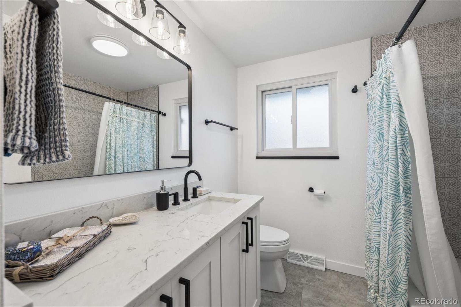 8257 Yarrow Court Arvada, CO 80005 - Photo 7 of 38 a bathroom with a granite countertop sink and a mirror