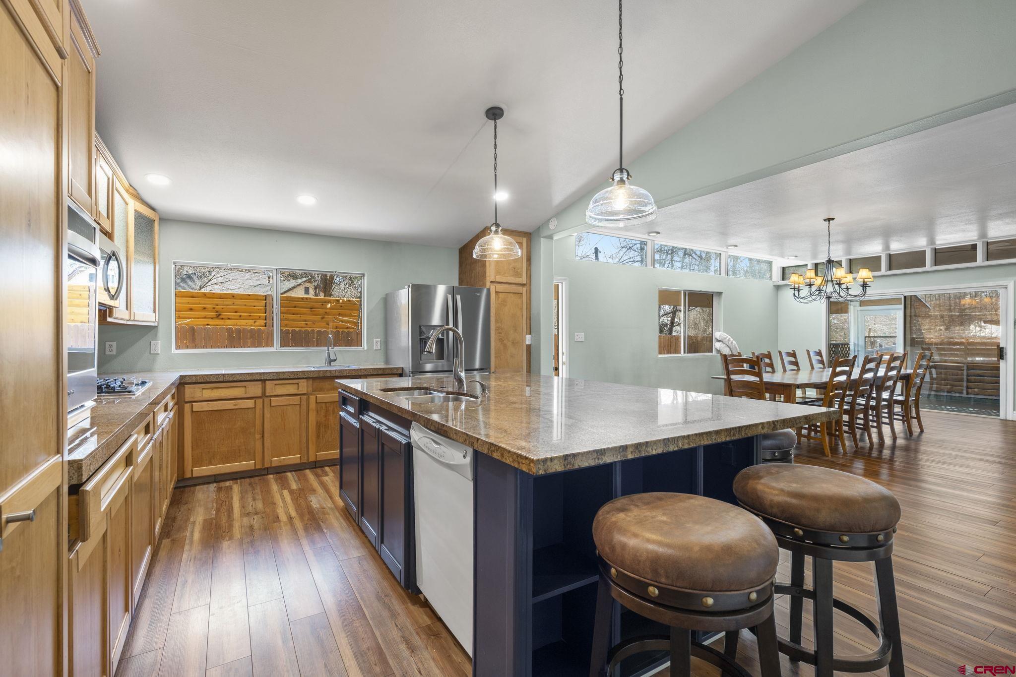 486 South Church Street Bayfield, CO 81122 - Photo 6 of 32 a kitchen with stainless steel appliances granite countertop a stove top oven a sink dishwasher a dining table and chairs with wooden floor