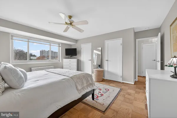 a bedroom with a large bed a chandelier and dresser