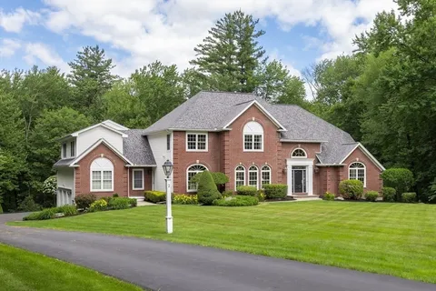 a front view of a house with a yard and trees
