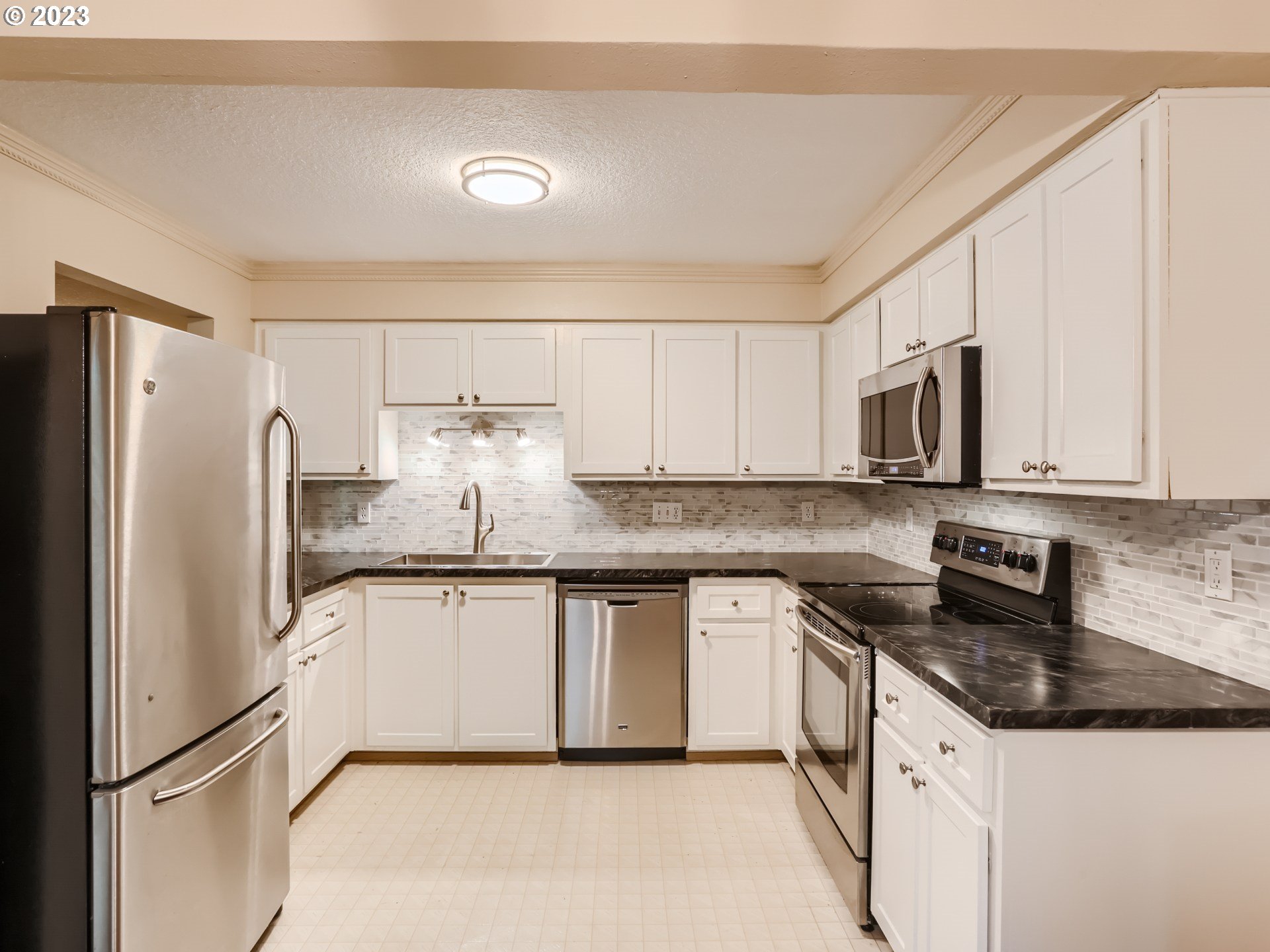 10660 Southwest Davies Road, Unit 30 Beaverton, OR 97008 - Photo 6 of 24 a kitchen with stainless steel appliances granite countertop a refrigerator a stove a sink and white cabinets