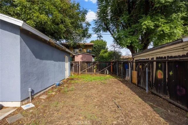 a backyard of a house with wooden fence and large trees