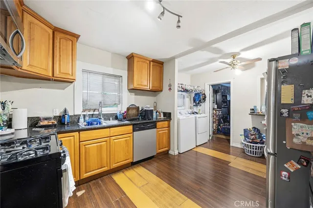 a kitchen with stainless steel appliances granite countertop a stove top oven a sink dishwasher and white cabinets with wooden floor