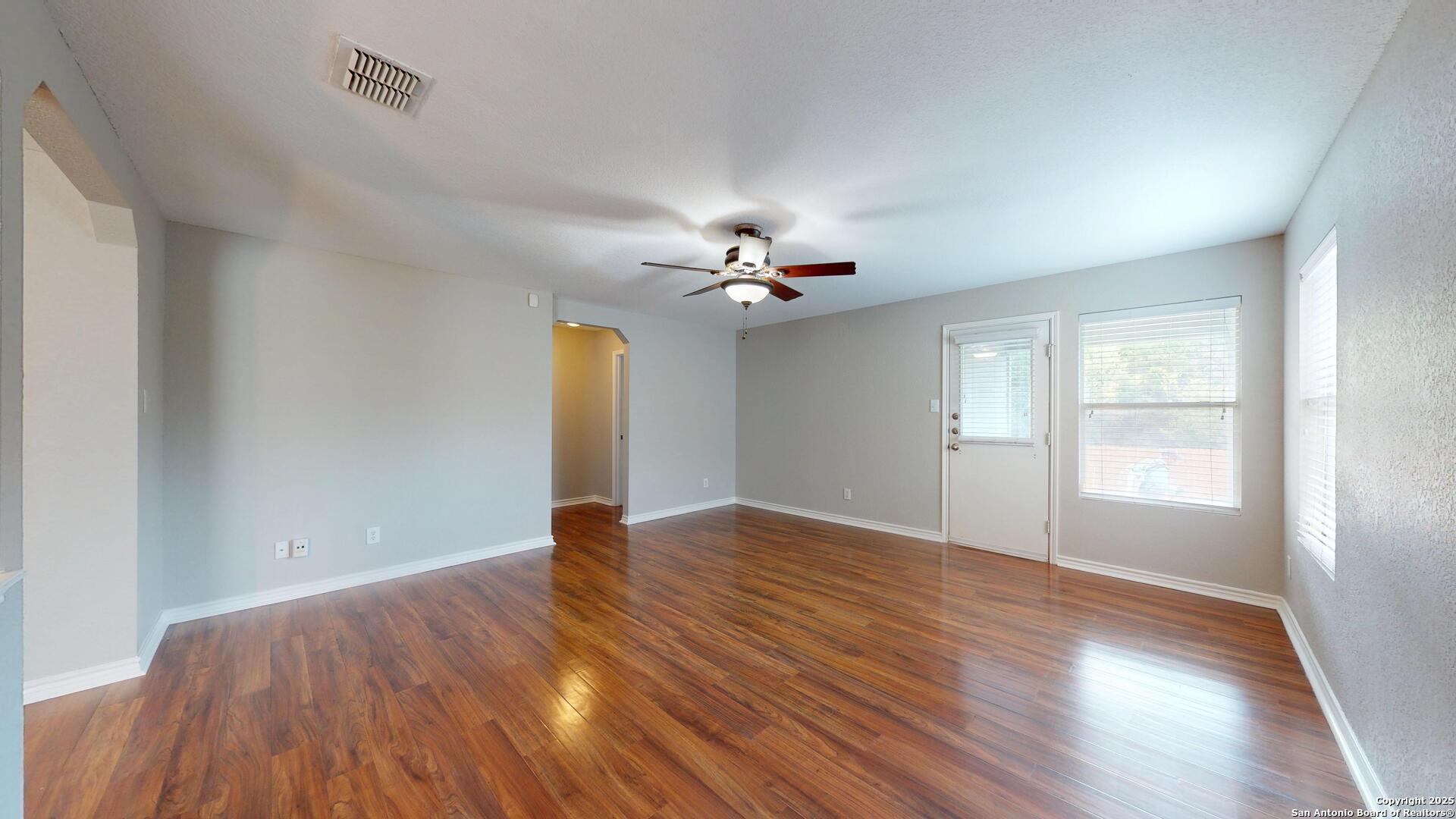 9515 Boatman Pier Converse, TX 78109 - Photo 17 of 41 an empty room with wooden floor chandelier fan and windows