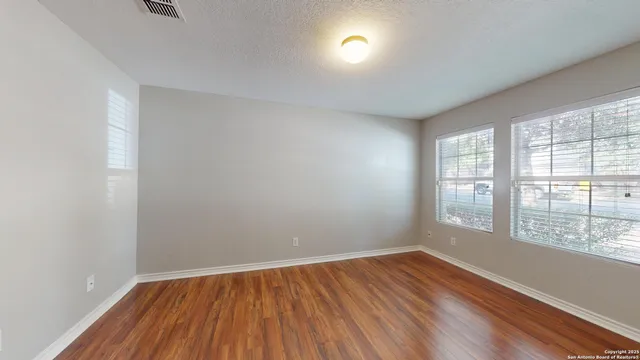 an empty room with wooden floor and windows