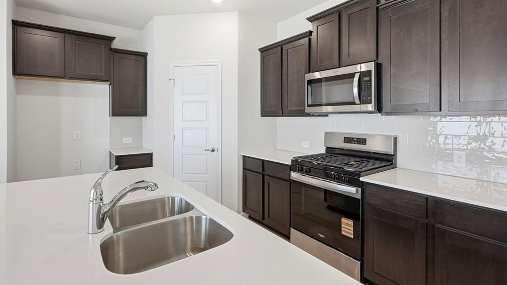 3513 Amaretto Road Aubrey, TX 76227 - Photo 11 of 34 a kitchen with a sink and a stove top oven