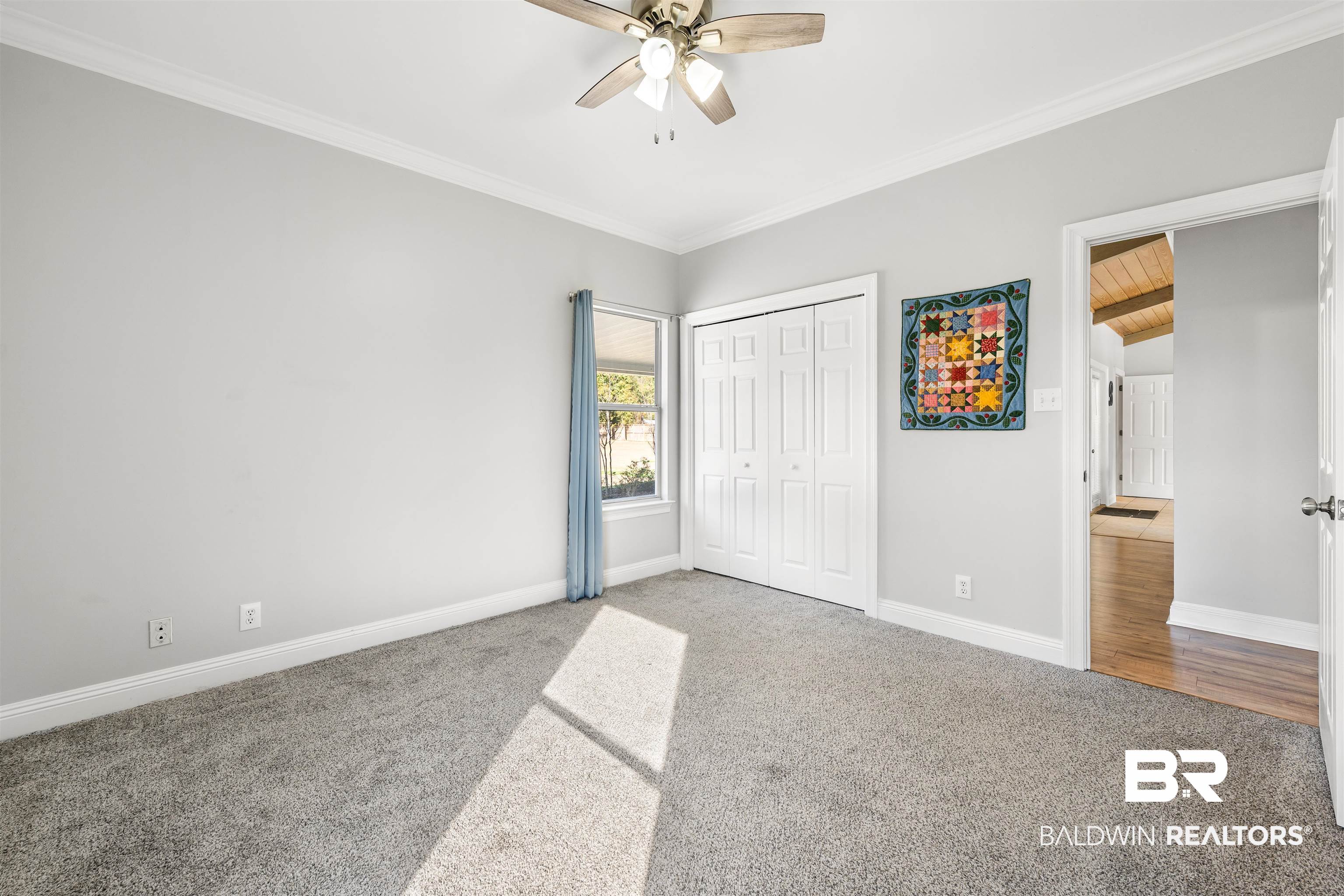 19079 Baldwin County Road 10 Foley, AL 36535 - Photo 15 of 37 Unfurnished bedroom featuring carpet, a closet, crown molding, a ceiling fan, and wood ceiling