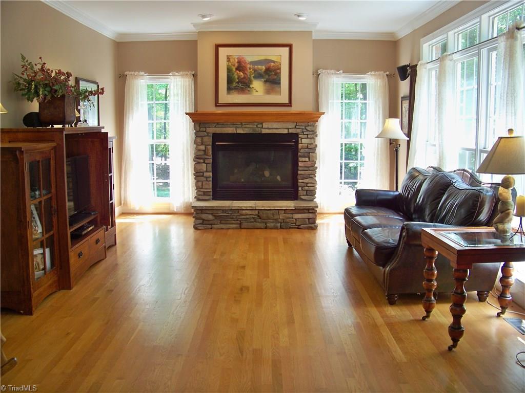 5805 Autumn Gate Drive Oak Ridge, NC 27310 - Photo 14 of 30 Stack stone fireplace surround, hardwood floors and a quad bank of windows makes this such an attractive room!