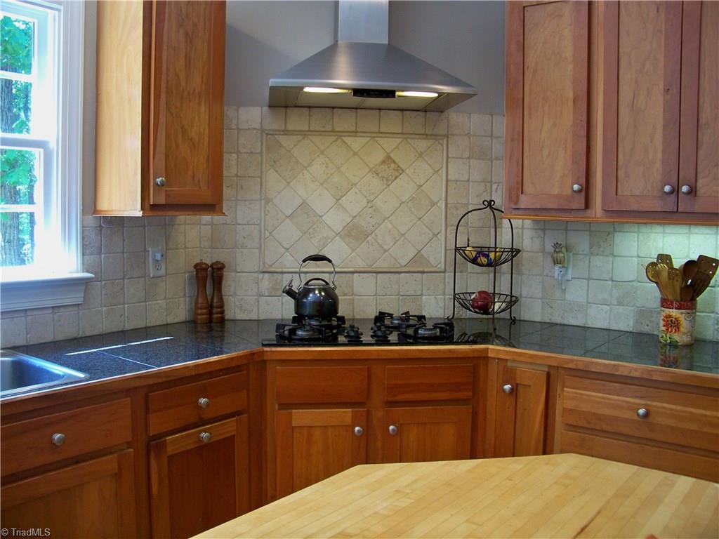 5805 Autumn Gate Drive Oak Ridge, NC 27310 - Photo 5 of 30 This is a chef's kitchen with a gas cooktop, an upscaled, vented range hood and a butcher block island!