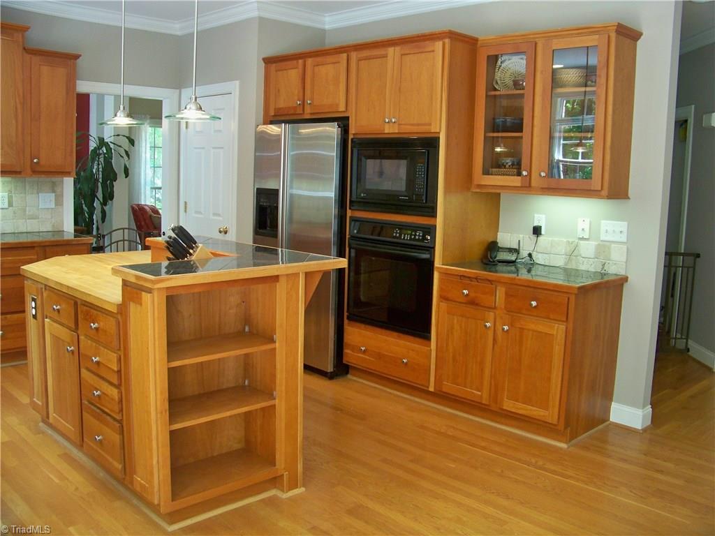 5805 Autumn Gate Drive Oak Ridge, NC 27310 - Photo 7 of 30 Nice display areas in the built in bookcase in island and the glass wall cabinet beside ovens.