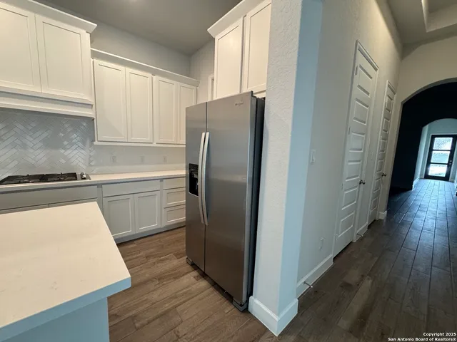 a kitchen with stainless steel appliances a refrigerator a sink and wooden floors