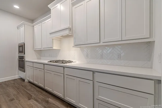 a kitchen with granite countertop white cabinets and stainless steel appliances