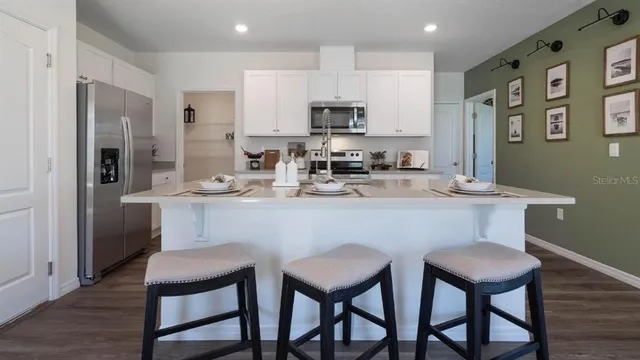 a kitchen with stainless steel appliances a dining table chairs refrigerator and sink