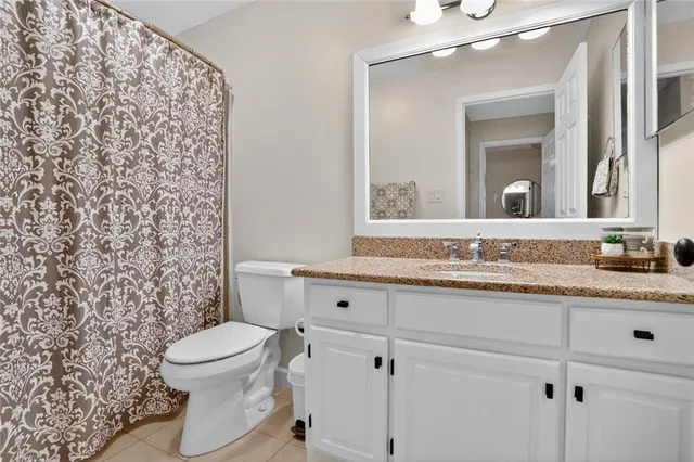 a bathroom with a granite countertop toilet sink mirror and