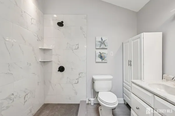 a bathroom with a granite countertop toilet a shower and a sink