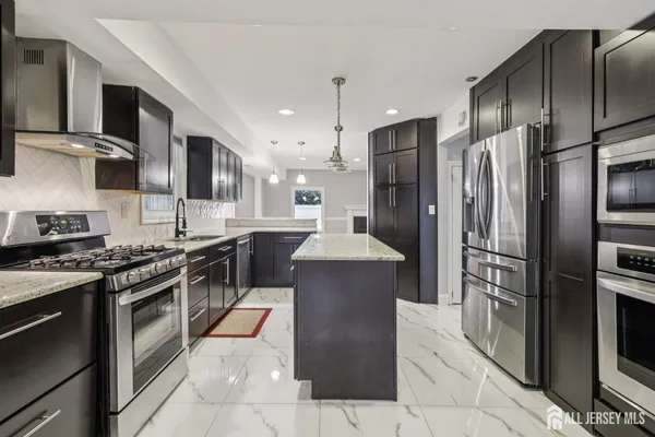 a large kitchen with stainless steel appliances granite countertop a stove a refrigerator and a sink