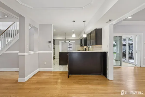 a view of kitchen with kitchen island granite countertop a refrigerator cabinets and wooden floor