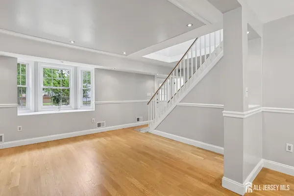 a view of an empty room with wooden floor and stairs