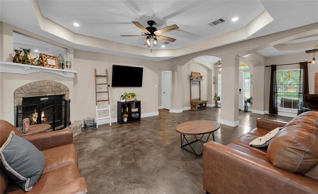 37 Bluebonnet Loop Morgan's Point Resort, TX 76513 - Photo 7 of 38 Spacious living area featuring a stone-surround fireplace with hearth, wood-finish flooring, tray ceilings with recessed lighting, and arched entryways