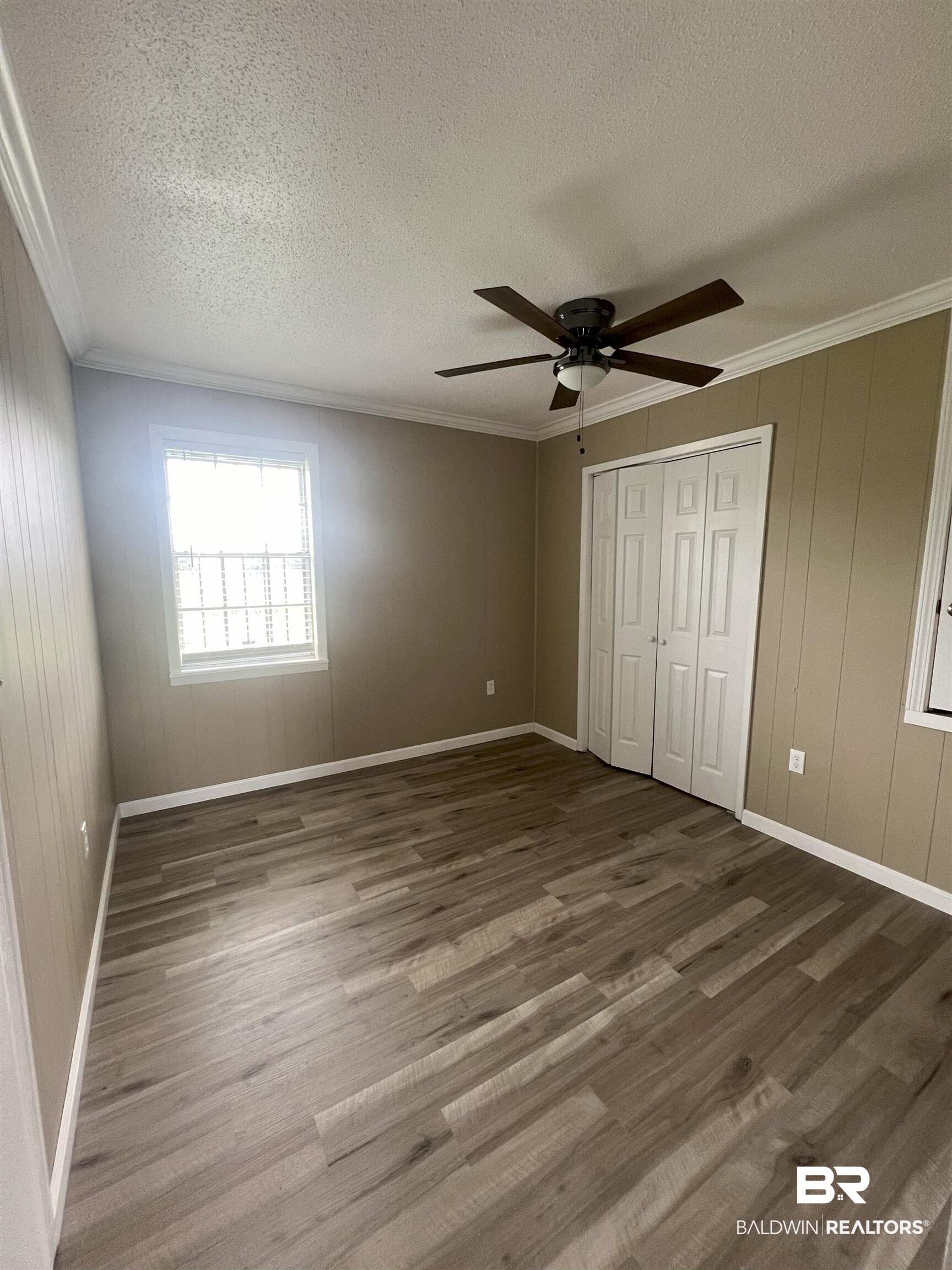 508 Freemanville Drive Atmore, AL 36502 - Photo 21 of 27 Unfurnished bedroom with a textured ceiling, ornamental molding, wood-type flooring, and ceiling fan