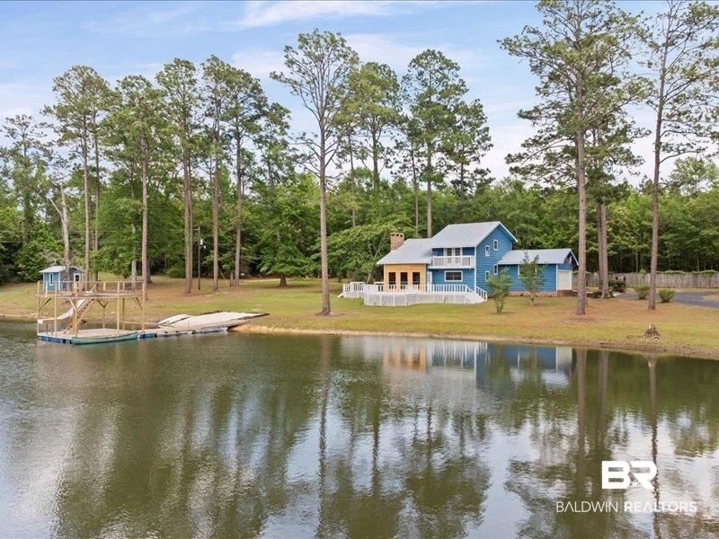 3160 Old Castleberry Road Brewton, AL 36426 - Photo 28 of 36 Waterfront property featuring a blue exterior, a spacious deck with white railings, and a multi-level dock with a covered structure