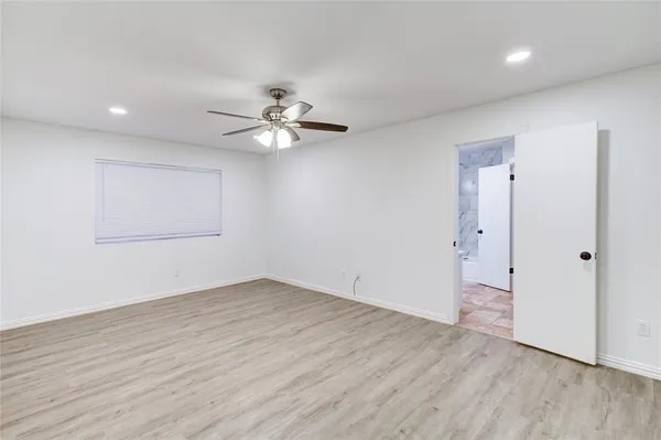 an empty room with wooden floor and ceiling fan