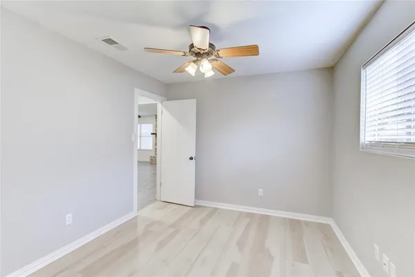 an empty room with windows and fan