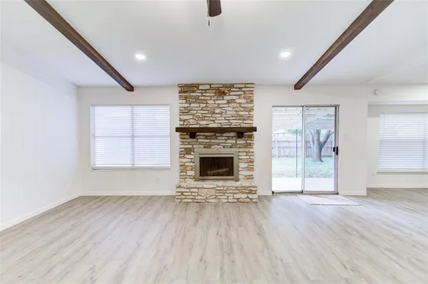 an empty room with wooden floor a fireplace and windows