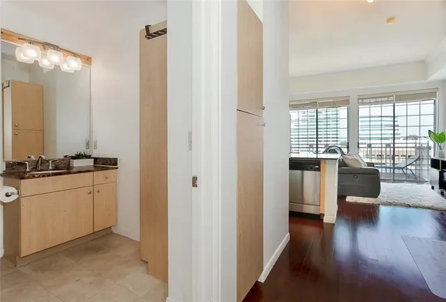 a open white kitchen with granite countertop a couch and a large window