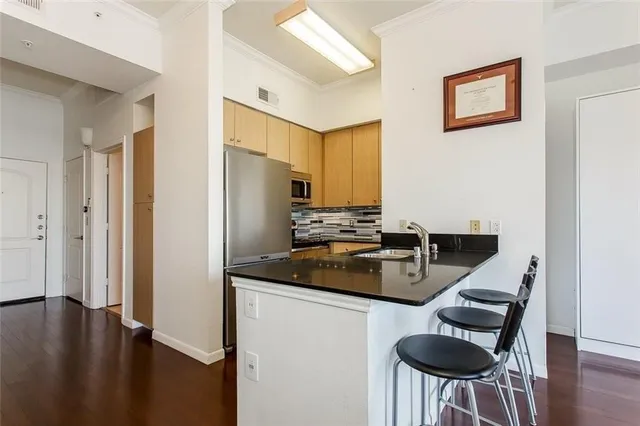 a kitchen with stainless steel appliances granite countertop a stove a refrigerator a sink a dining table and chairs with wooden floor