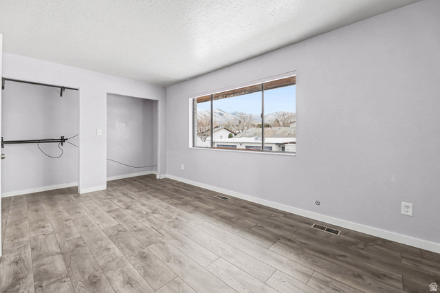 34 Benchmark Village Tooele, UT 84074 - Photo 19 of 35 Unfurnished bedroom with light wood finished floors, a textured ceiling, and two closets