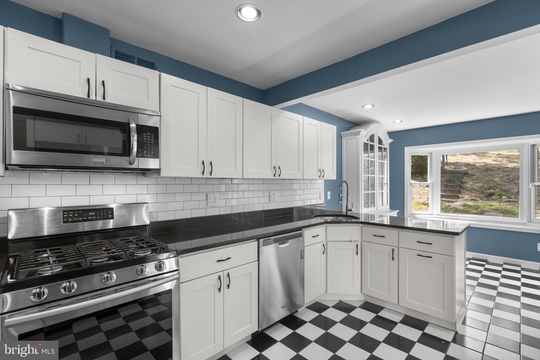 822 Loxford Terrace Silver Spring, MD 20901 - Photo 20 of 61 a kitchen with stainless steel appliances a sink a stove a microwave cabinets and a window