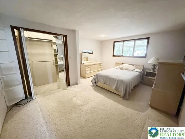 a bedroom with a bed and a large mirror next to a window
