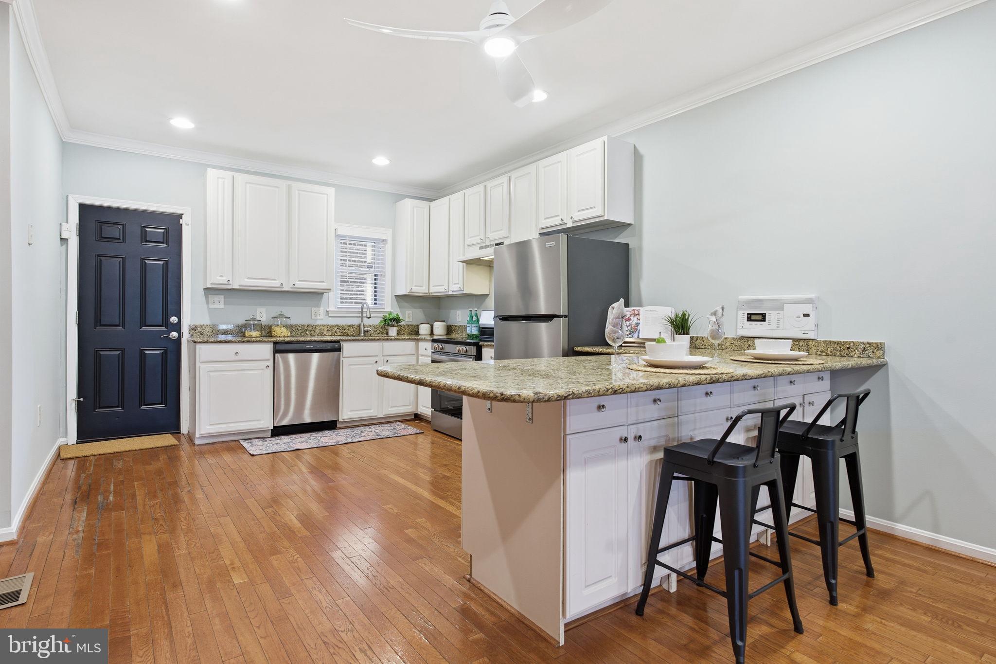 3135 Fait Avenue Baltimore, MD 21224 - Photo 7 of 35 a kitchen with stainless steel appliances granite countertop a stove top oven a refrigerator a sink and a island with wooden floor