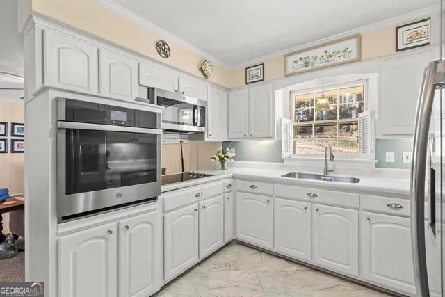 a kitchen with stainless steel appliances granite countertop white cabinets a sink and a window