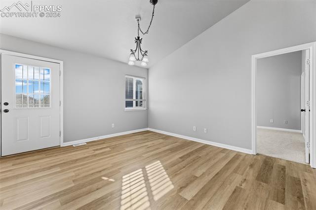 7515 Farmcrest Road Colorado Springs, CO 80925 - Photo 5 of 40 Unfurnished dining area featuring a chandelier, lofted ceiling, and light hardwood / wood-style floors