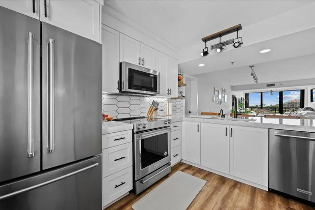 a kitchen with cabinets stainless steel appliances and wooden floor