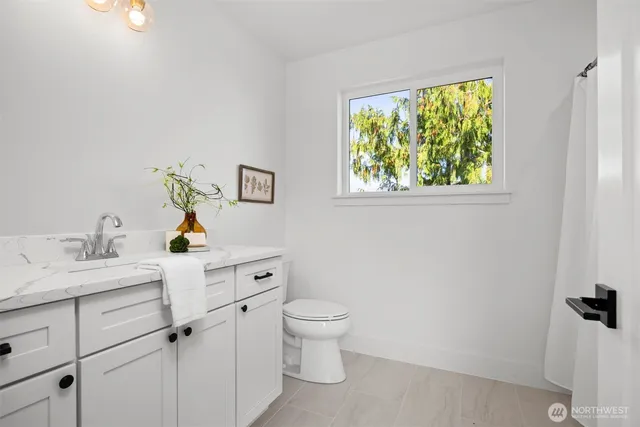 a view of bathroom with a window double vanity sink and a toilet